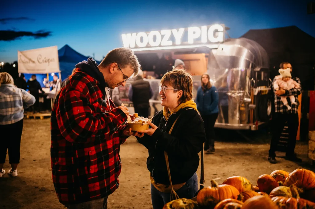 Couple enjoying food in front of street food vendor at pumpkins