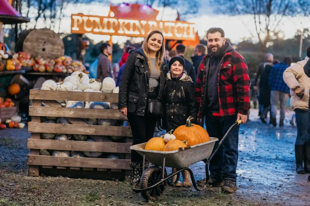 Family in front of pumpkins and patch sign