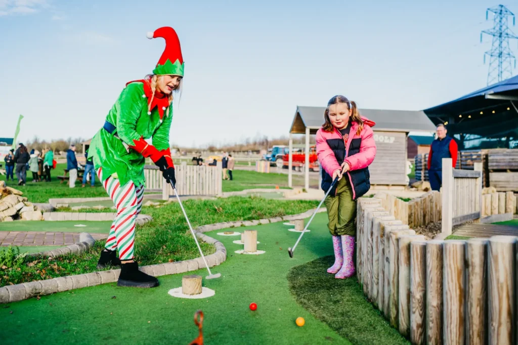 Child and Elf playing mini golf at Christmas in the farm park