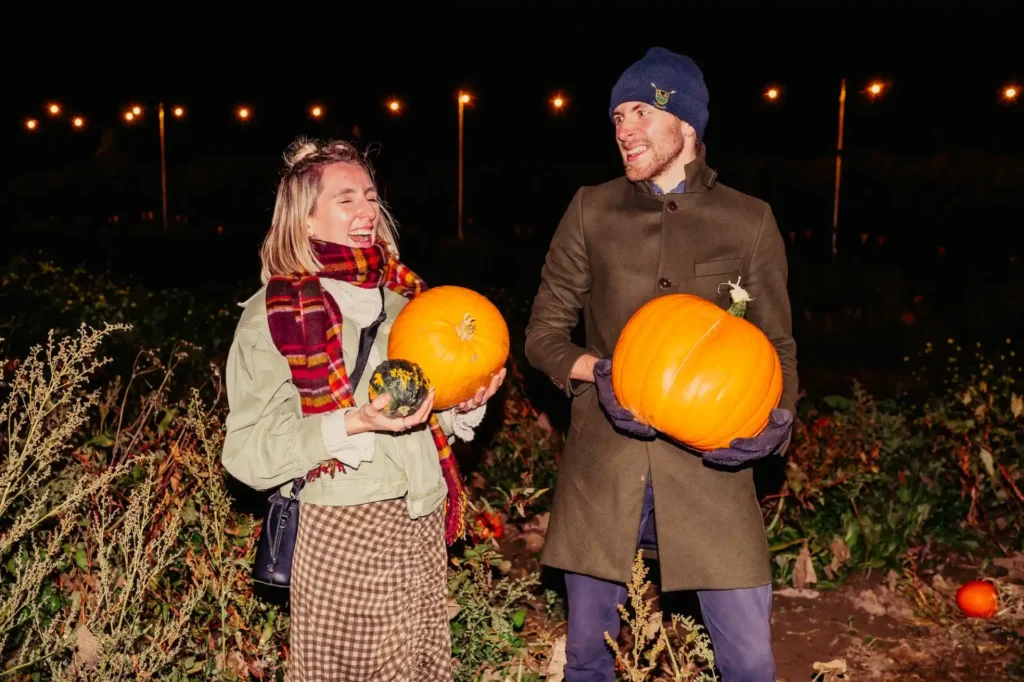 Couple laughing out in pumpkin patch at night